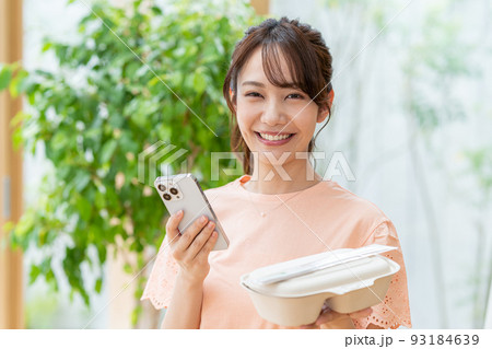 お弁当とスマホを持つ若い女性 93184639