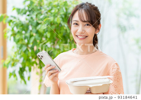 お弁当とスマホを持つ若い女性 93184641