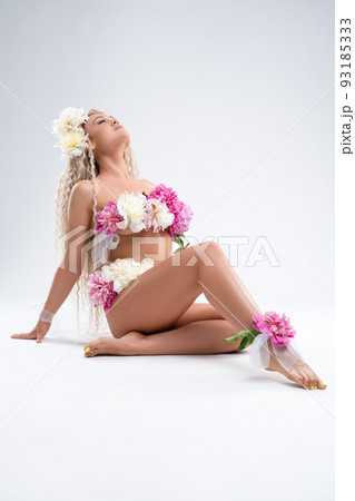Graceful naked lady with fresh flowers on body sitting in light studio Graceful naked lady with fresh flowers on body sitting in light studio 93185333