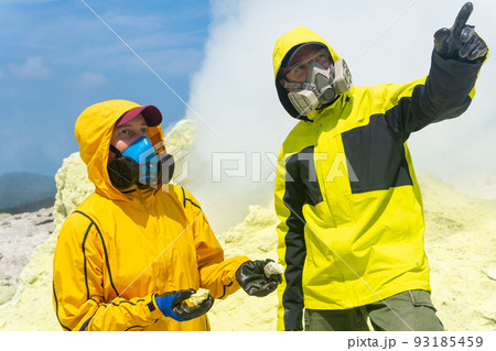 volcanologists on the slope of the volcano collect samples of minerals against the backdrop of smoking sulfur fumaroles 93185459