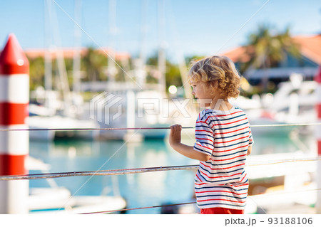 Child watching yacht and boat in harbor. Yachting. 93188106