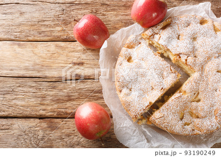 Homemade apple pie charlotte and piece of cake close-up on a parchment paper. Horizontal top view from above 93190249