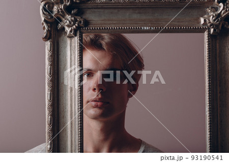 Millenial young man artist with blonde hair on gilded picture frame portrait. Millenial young man artist with blonde hair on gilded picture frame portrait. 93190541