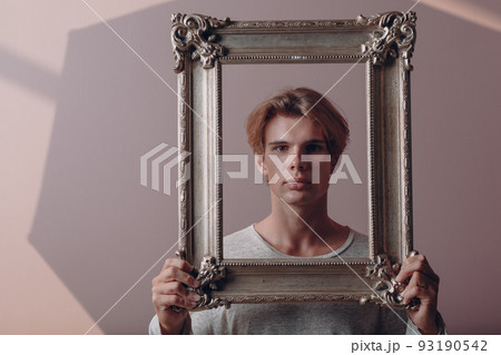 Millenial young man artist with blonde hair on gilded picture frame portrait. 93190542
