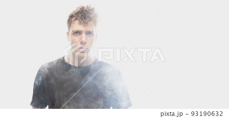 Smoke enveloped young man. Model looking at camera isolated over white background with clouds of smoke. Concept of mental health, art, emotions Smoke enveloped young man. Model looking at camera isolated over white background with clouds of smoke. Concept of mental health, art, emotions 93190632