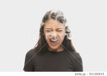 Shouting young girl with dark hair releases smoke from the mouth isolated over white background. Concept of mental health, art, human emotions 93190645