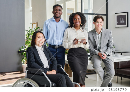 Portrait of multiethnic business team with colleague with disability smiling at camera standing at office Portrait of multiethnic business team with colleague with disability smiling at camera standing at office 93193779