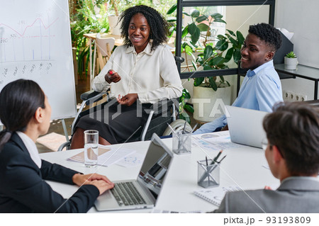 African businesswoman with disability talking to her colleagues at table during meeting at office African businesswoman with disability talking to her colleagues at table during meeting at office 93193809