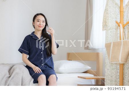 パジャマ姿でミネラルウォーターを飲む若い女性 パジャマ姿でミネラルウォーターを飲む若い女性 93194571