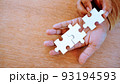 two hand put white jigsaw puzzle together on his hand. 93194593