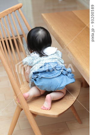 ダイニングの椅子に登って遊ぶ1歳の女の子の赤ちゃん ダイニングの椅子に登って遊ぶ1歳の女の子の赤ちゃん 93200589