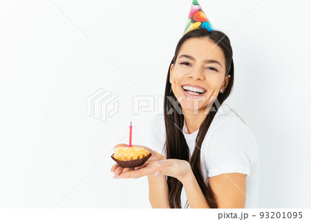 Portrait of happy young woman in party hat holding cake 93201095