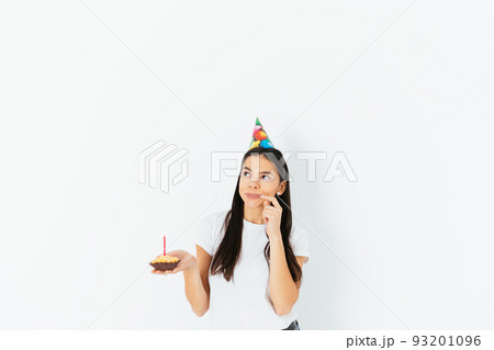 Making birthday wish, brunette woman wearing celebration cap 93201096