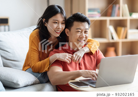 Happy japanese lovers planning vacation, using computer 93202165