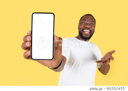 Cheerful Black Man Showing Huge Smartphone Empty Screen, Yellow Background 93202455