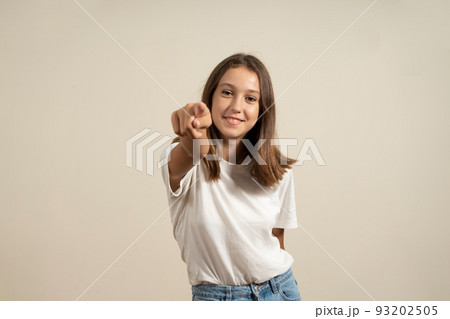 I choose you and command you. The smiling teenage girl pointing at camera, half-length close-up portrait on beige studio background. Human emotions, facial expression concept. Front view. I choose you and command you. The smiling teenage girl pointing at camera, half-length close-up portrait on beige studio background. Human emotions, facial expression concept. Front view. 93202505
