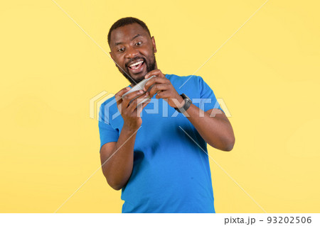 Excited Black Guy Playing Mobile Game On Cellphone, Yellow Background Excited Black Guy Playing Mobile Game On Cellphone, Yellow Background 93202506