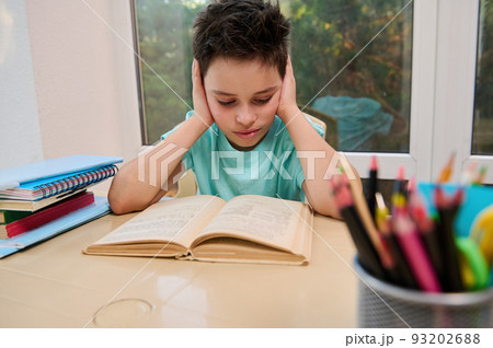 Serious smart teenage schoolboy reads text in textbook while doing literature homework. Erudition. Back to school. Open to new knowledge in the new semester of the new academic year. Online education Serious smart teenage schoolboy reads text in textbook while doing literature homework. Erudition. Back to school. Open to new knowledge in the new semester of the new academic year. Online education 93202688