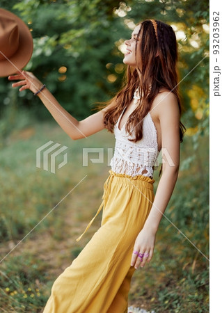A young hippie woman dancing merrily and smiling earnestly in nature in the fall. The concept of economical consumption and self-care A young hippie woman dancing merrily and smiling earnestly in nature in the fall. The concept of economical consumption and self-care 93203962