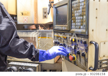 町の金属加工工場、機械の操作パネルの操作風景 93206158