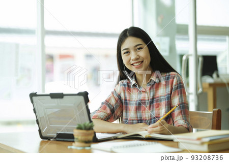 Young asian woman study in front of the laptop computer and and using headphones at offsite.. 93208736