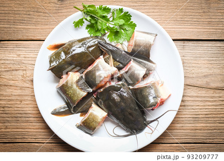 catfish fillet on white plate, fresh raw catfish menu freshwater fish, catfish for cooking food, fish chopped with ingredients coriander on wooden background catfish fillet on white plate, fresh raw catfish menu freshwater fish, catfish for cooking food, fish chopped with ingredients coriander on wooden background 93209777