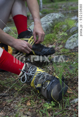 view of torn hiking boots on the feet of a person, a tourist, on which he wound an insulating tape view of torn hiking boots on the feet of a person, a tourist, on which he wound an insulating tape 93210680