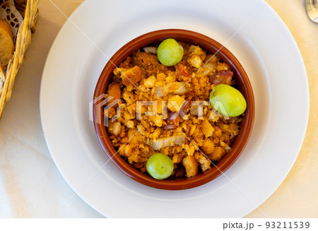 Migas pastoriles from fried crumbled bread with bacon and chorizo served with grapes 93211539
