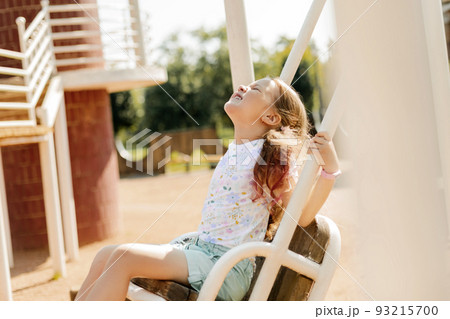 A charming girl is having fun on a swing on a summer day. Childhood, recreation, summer time A charming girl is having fun on a swing on a summer day. Childhood, recreation, summer time 93215700