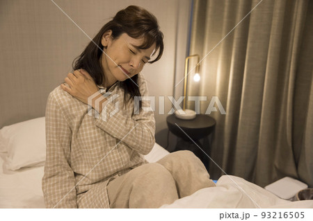 寝室で肩を摩るミドル女性 93216505
