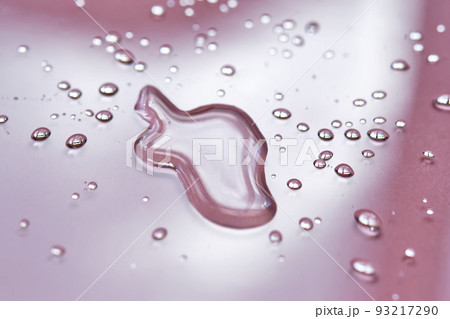 A large drop and splashes of micellar water on a pink background. A large drop and splashes of micellar water on a pink background. 93217290