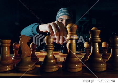 Young adult handsome man playing chess in dark with side lit. Young adult handsome man playing chess in dark with side lit. 93222148