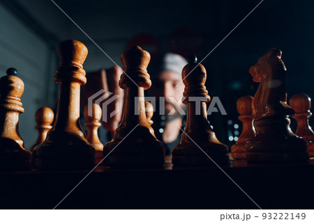 Young adult handsome man playing chess in dark with side lit. 93222149