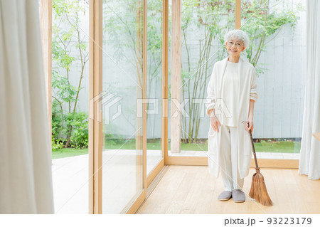 箒で部屋を掃除するシニア女性 箒で部屋を掃除するシニア女性 93223179