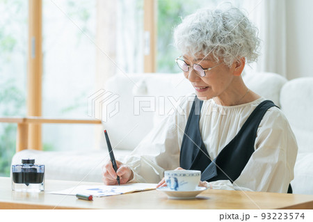 リビングで手紙を書くシニア女性 93223574