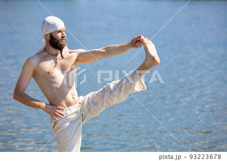 One young bearded man meditating yoga on river berth at sunrise, outdoors. Concept of mental health, relaxation, harmony with nature 93223678