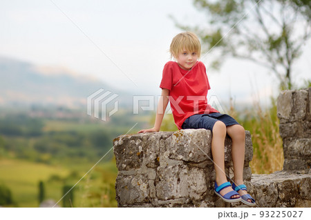 Little child tourist visits famous fortress Rozafa near Shkodra city. Boy watching ancient stone walls and towers of bastion. Interest in history of children. Travel and tourism 93225027