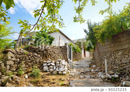 Authentic street of Albanian village on the shore of Lake Skadar. Rustic view with rock fences, houses and gardens. Authentic street of Albanian village on the shore of Lake Skadar. Rustic view with rock fences, houses and gardens. 93225235