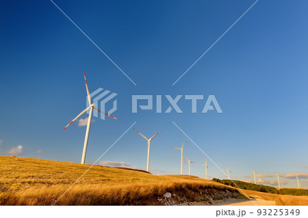 Power stations for renewable electric energy production. Windmills on sunny summer day. High wind turbines for generation electricity. Green energy Power stations for renewable electric energy production. Windmills on sunny summer day. High wind turbines for generation electricity. Green energy 93225349