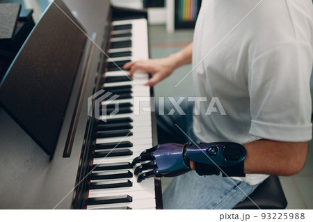 Young disabled man play on piano electronic synthesizer with artificial prosthetic hand in music shop Young disabled man play on piano electronic synthesizer with artificial prosthetic hand in music shop 93225988