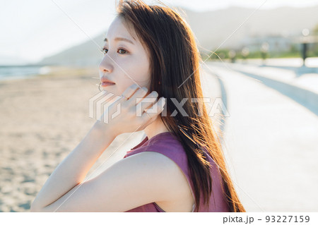 海を眺めるワンピースの若い女性 93227159