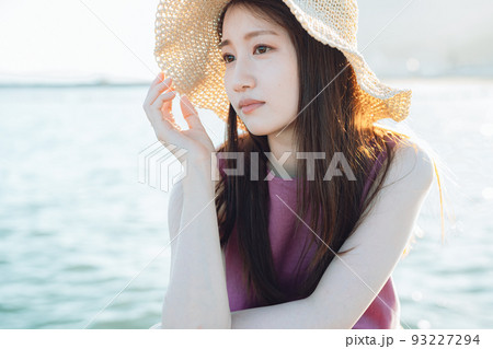 海を眺める麦わら帽子の若い女性 海を眺める麦わら帽子の若い女性 93227294