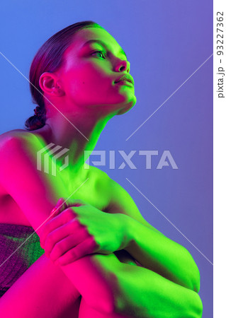 Portrait of young, beautiful and healthy girl with well-kept skin isolated on dark background in neon light. Art, fashion, style, facial expression Portrait of young, beautiful and healthy girl with well-kept skin isolated on dark background in neon light. Art, fashion, style, facial expression 93227362