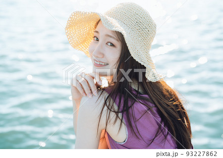 海辺でこちらを見る麦わら帽子の女性 海辺でこちらを見る麦わら帽子の女性 93227862