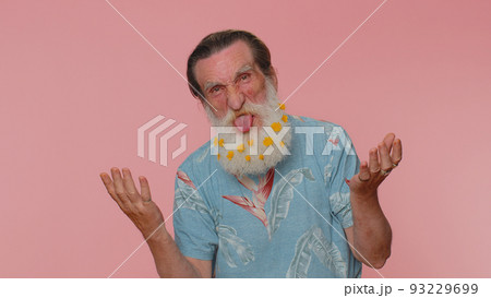 Funny joyful man making playful silly facial expressions, grimacing, fooling around showing tongue 93229699