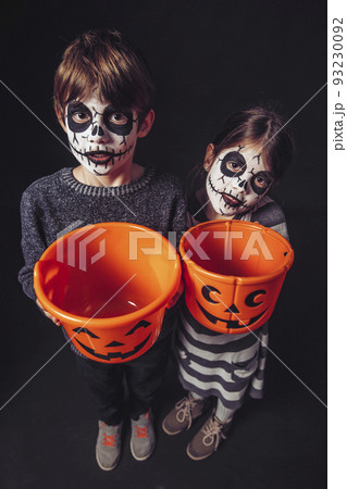 Two kids holding pumpkin buckets at Halloween Two kids holding pumpkin buckets at Halloween 93230092
