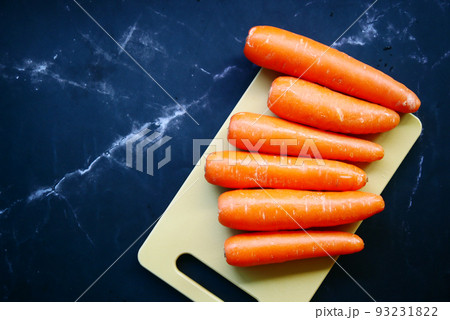 fresh carrots on chopping board on table  93231822