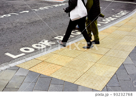 Tactile tiles for the blind. Panels for the blind laid on asphalt. Guide tape for the disabled. People cross the road at a traffic light for the blind. 93232768