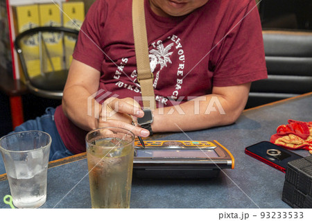 スナックのカウンターでカラオケの選曲をする男性 スナックのカウンターでカラオケの選曲をする男性 93233533