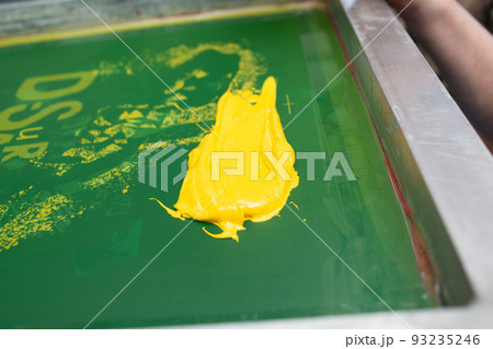 Serigraphy silk screen print process at clothes factory. Frame, squeegee and plastisol color paints. 93235246